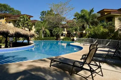 a swimming pool with two chairs next to a resort at Juanderlust - 2 Bedroom Condo in Tamarindo