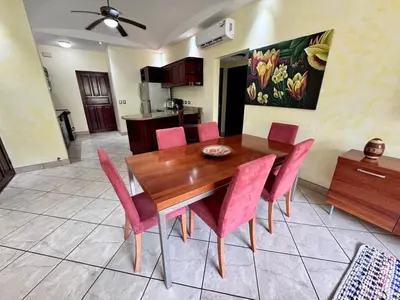 a dining room with a wooden table and pink chairs at Juanderlust - 2 Bedroom Condo in Tamarindo