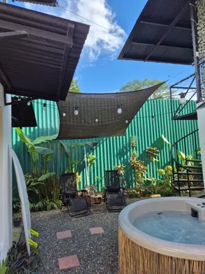 a hot tub in a patio with chairs and a green fence at La Casa de Pepa y Poli with Jacuzzi and free bikes in Uvita