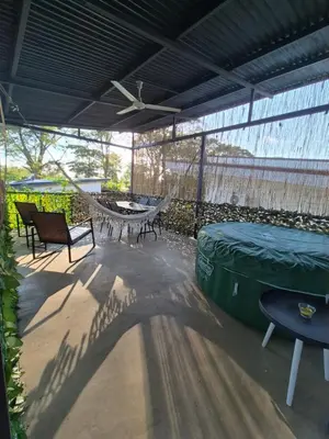 a covered patio with a table and chairs and a table and a table at La Casa de Pepa y Poli with Jacuzzi and free bikes in Uvita
