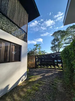 a white building with a fence next to it at La Casa de Pepa y Poli with Jacuzzi and free bikes in Uvita