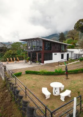 a house with a table and benches in front of it at Loft con hermosas vistas y Volcán Turrialba in Turrialba