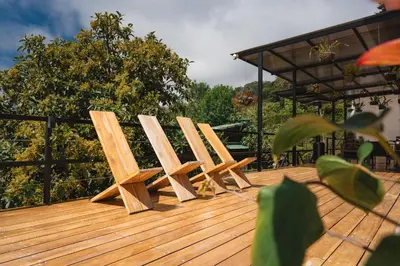 a row of wooden chairs sitting on a deck at Loft con hermosas vistas y Volcán Turrialba in Turrialba