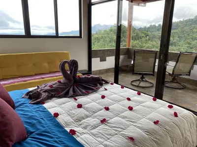 a bed with red flowers on it in a room with windows at Romantic Retreat Volcano View! River Trail! in El Castillo de la Fortuna