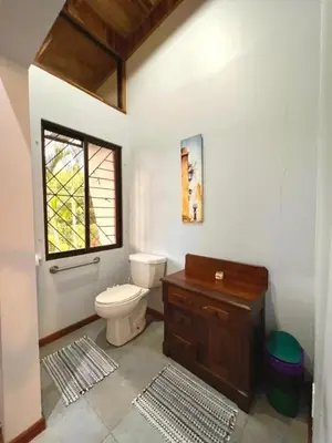 a bathroom with a toilet and a window at Romantic Retreat Volcano View! River Trail! in El Castillo de la Fortuna