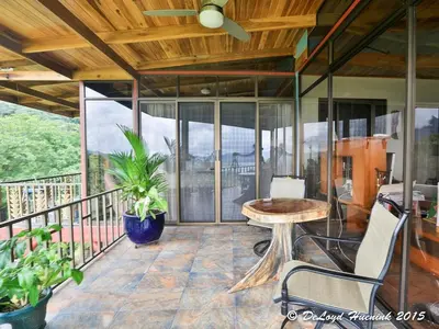 a screened in porch with a table and chairs at Romantic Retreat Volcano View! River Trail! in El Castillo de la Fortuna