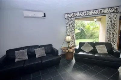 a living room with a black leather couch and a window at Firefly Hilltop Retreat, Swimming Pool Volcano! in El Castillo de La Fortuna