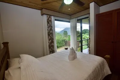 a bedroom with a bed and a large window at Firefly Hilltop Retreat, Swimming Pool Volcano! in El Castillo de La Fortuna