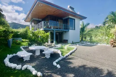 a house with a table and benches in front of it at Firefly Hilltop Retreat, Swimming Pool Volcano! in El Castillo de La Fortuna