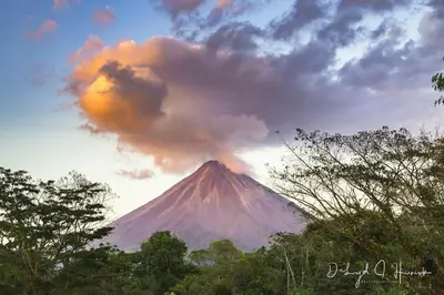 a volcano with a cloud above it with trees at Laughing Falcon Studio in El Castillo de La Fortuna