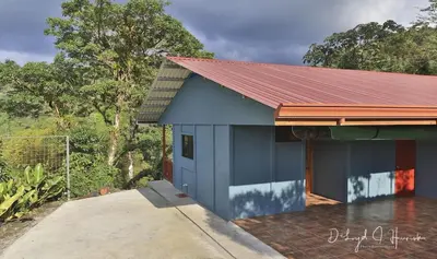 a blue house with a red roof at Laughing Falcon Studio in El Castillo de La Fortuna