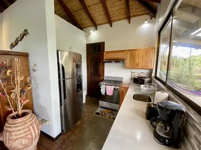 a kitchen with a refrigerator and a counter top at Birdsong Villa, Romantic Suite W- Jacuzzi in El Castillo de La Fortuna