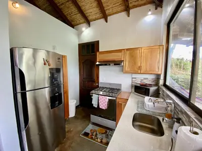a kitchen with a stainless steel refrigerator and wooden cabinets at Arenal Birdsong, Entire Villa W- Stunning Views,! in El Castillo de La Fortuna