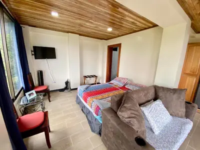 a bedroom with a bed and a couch and a tv at Arenal Birdsong, Entire Villa W- Stunning Views,! in El Castillo de La Fortuna