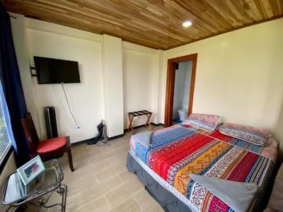 a bedroom with a bed and a flat screen tv at Arenal Birdsong, Entire Villa W- Stunning Views,! in El Castillo de La Fortuna