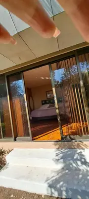 a person standing in front of a house with large windows at Bed and breakfast close to airport, beaches and attractions in Alajuela City