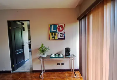 a table in a room with a door and a table with a plant at Bed and breakfast close to airport, beaches and attractions in Alajuela City