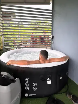 a man laying in a hot tub in front of a window at The Slothie's House in Tapantí