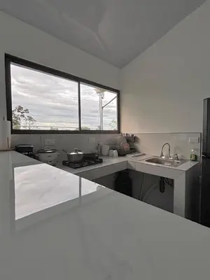 a white kitchen with a sink and a window at The Slothie's House in Tapantí