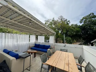 a patio with a wooden table and blue cushioned furniture at Charming Nook Second Floor Condo with Rooftop in Coco