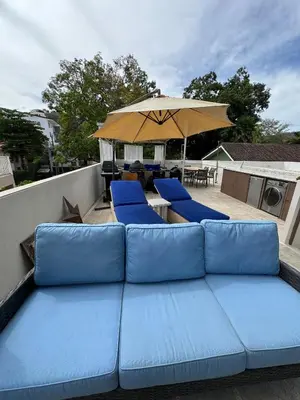 a blue couch on a patio with an umbrella at Charming Nook Second Floor Condo with Rooftop in Coco