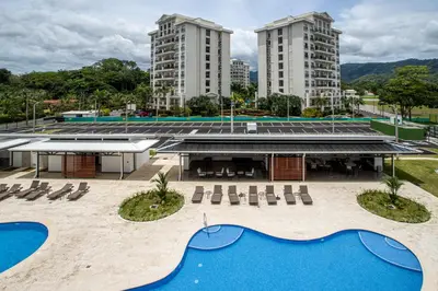 a view of a building with a pool and two tall buildings at Viva Jaco II in Jacó