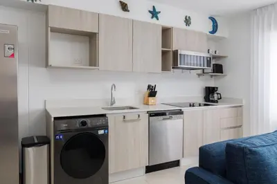 a kitchen with a washing machine and a blue chair at Viva Jaco in Jacó