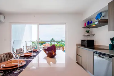 a kitchen with a table with chairs and a window at Viva Jaco in Jacó