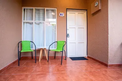 two green chairs and a table in front of a door at Villas Paraiso B52 in Jacó