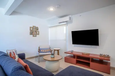 a living room with a blue couch and a flat screen tv at Viva Jaco 04 02B in Jacó