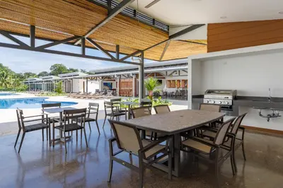 a dining room with tables and chairs and a swimming pool at Viva Jaco II in Jacó