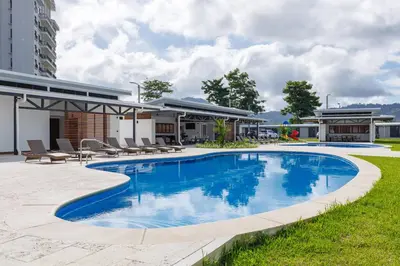 a swimming pool with chairs and a building at Viva Jaco II in Jacó