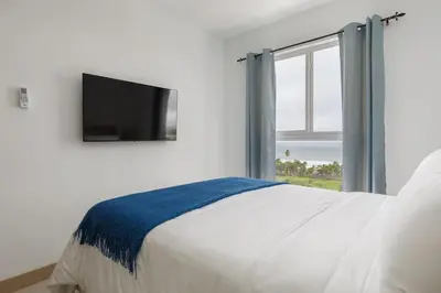 a bedroom with a bed with a tv and a window at Viva Jaco in Jacó