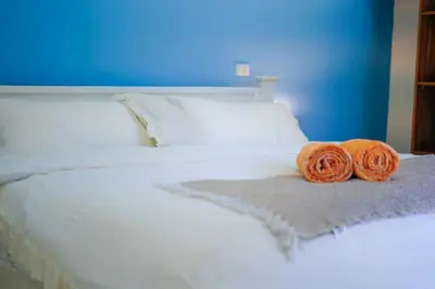 two orange towels sitting on a white bed at Blue 2BR 2BA 10 Min Beach Walk in Nosara