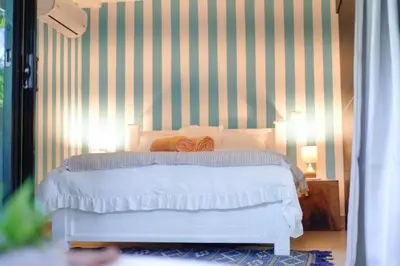 a bedroom with a white bed with a striped wall at Blue 2BR 2BA 10 Min Beach Walk in Nosara