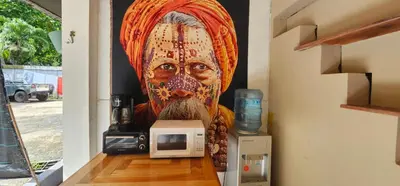 a large painting of a man on a wall next to a microwave at Santa Toro, private rooms close to the beach in Santa Teresa Beach