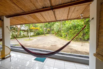 a hammock in a house with a view of a yard at Santa Toro, private rooms close to the beach in Santa Teresa Beach