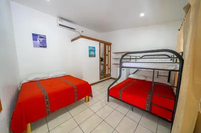 two bunk beds in a room with red sheets at Santa Toro, private rooms close to the beach in Santa Teresa Beach