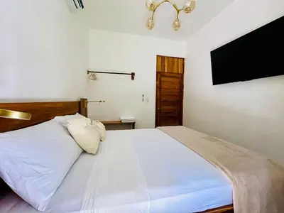 a bedroom with a white bed and a flat screen tv at Casa Sol in Naranjito