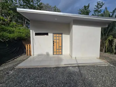 a small white building with a brown door at Apartamento Las Tecas in Quepos