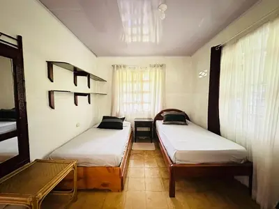 a bedroom with two beds and a table and a window at Casa de Campo en Rivas de Pérez Zeledon in Rivas