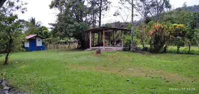 a small shelter in a grassy field with a house at Casa de Campo en Rivas de Pérez Zeledon in Rivas