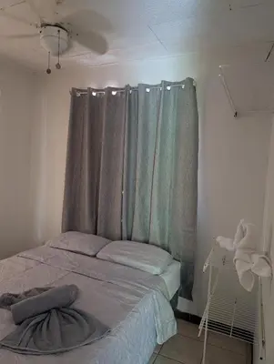 a bedroom with a bed with a curtain and a window at Pura Vida Paz y Amor in Quepos