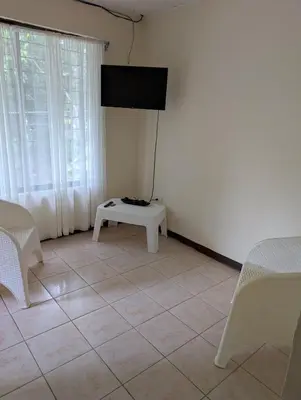 a living room with a tv on a white wall at Pura Vida Paz y Amor in Quepos