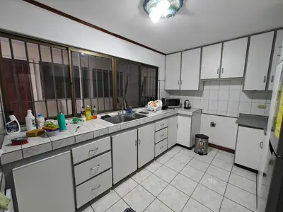 a large kitchen with white cabinets and appliances at House in Rohrmoser near the National Stadium of CR in San José