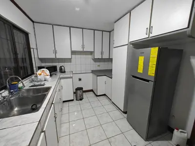 a kitchen with white cabinets and a stainless steel refrigerator at House in Rohrmoser near the National Stadium of CR in San José