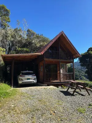 a house with a car parked in front of it at El Quetzalito Cabin in San Gerardo de Dota