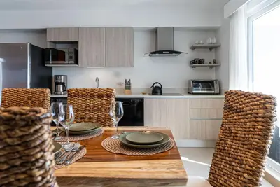 a kitchen with a wooden table with plates and wine glasses at Viva Jaco II in Jacó