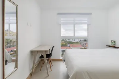 a bedroom with a bed and a desk and a mirror at Viva Jaco in Jacó