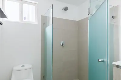 a bathroom with a glass shower stall and a toilet at Viva Jaco in Jacó